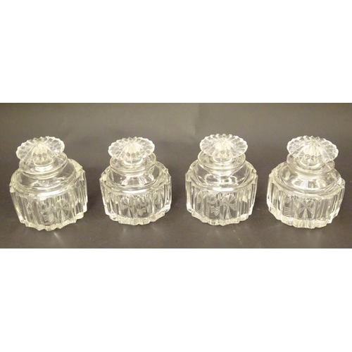 119 - A set of four 19thC glass scent bottles and stoppers with cut decoration within a wooden box. Each s... 