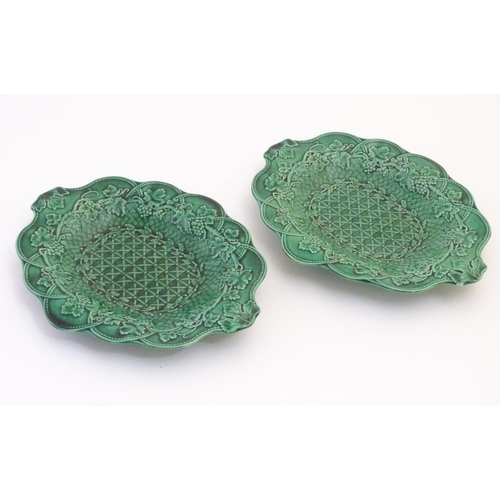 94 - A pair of Wedgwood majolica oval plates with a green lustre glaze, decorated with moulded grape vine... 