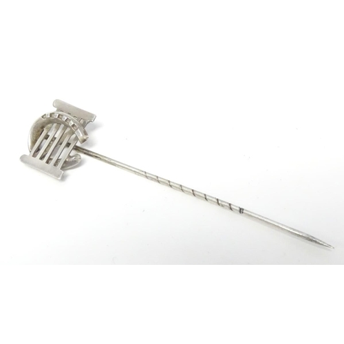 209 - A white metal stick pin surmounted by a horseshoe and gate. Approx 3'' long