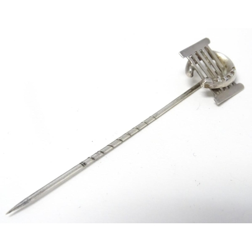 209 - A white metal stick pin surmounted by a horseshoe and gate. Approx 3'' long