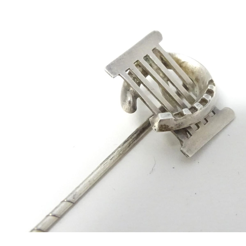 209 - A white metal stick pin surmounted by a horseshoe and gate. Approx 3'' long