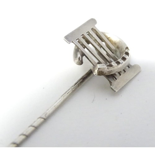 209 - A white metal stick pin surmounted by a horseshoe and gate. Approx 3'' long