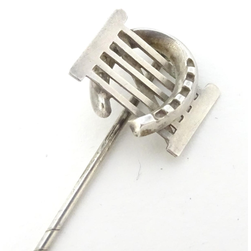 209 - A white metal stick pin surmounted by a horseshoe and gate. Approx 3'' long