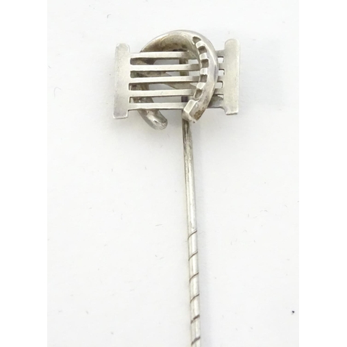 209 - A white metal stick pin surmounted by a horseshoe and gate. Approx 3'' long