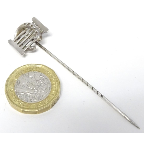 209 - A white metal stick pin surmounted by a horseshoe and gate. Approx 3'' long