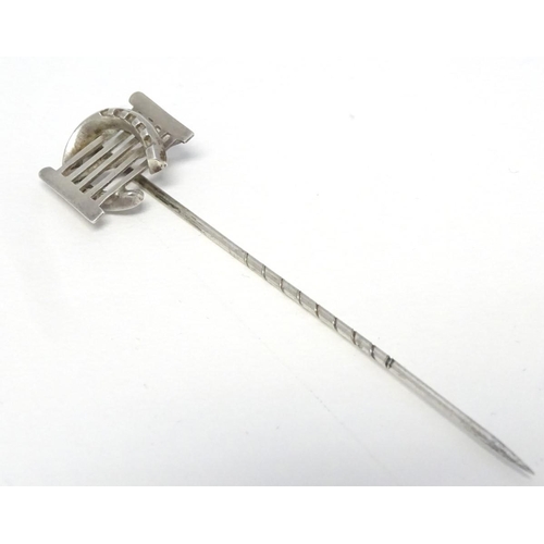 209 - A white metal stick pin surmounted by a horseshoe and gate. Approx 3'' long