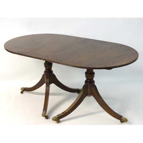 183 - An early 20thC mahogany Regency style dining table, with splayed fluted sabre legs terminating in br... 