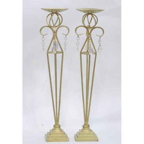 203 - A pair of tall gilt candle sticks with glass drops