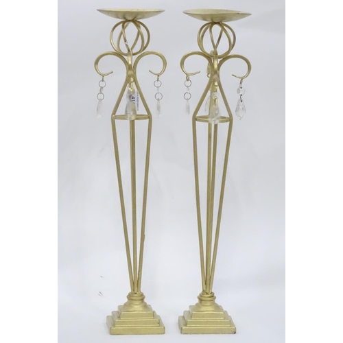 203 - A pair of tall gilt candle sticks with glass drops