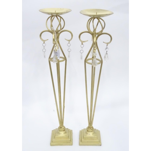 203 - A pair of tall gilt candle sticks with glass drops