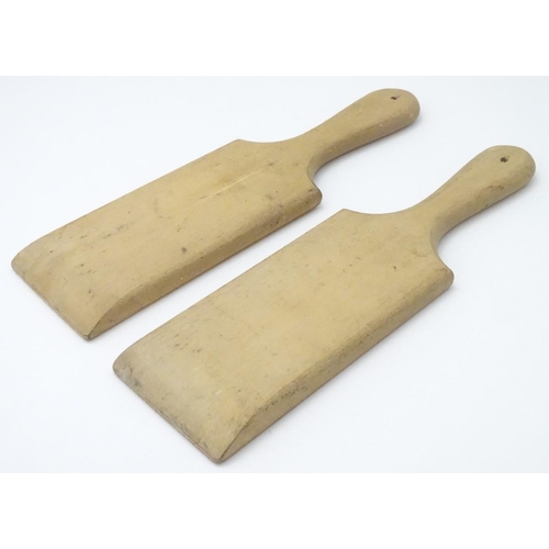 223 - A pair of late 19th / early 20thC carved beech butter pats, each 11'' long.