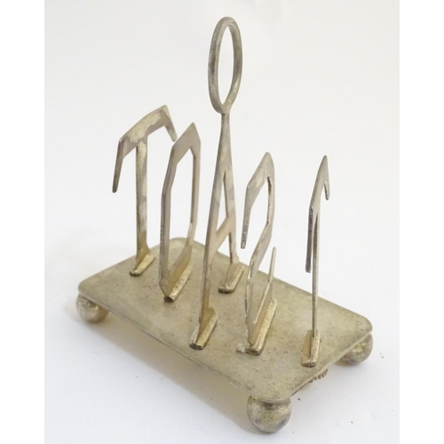 357 - A 21stC silver plated toast rack, the divisions formed as the letters 'TOAST'. 4 1/4'' long, 5'' tal... 