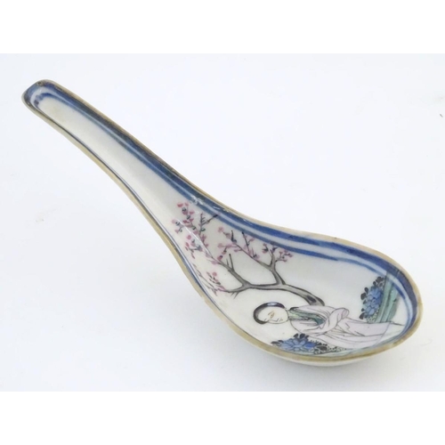 14 - A Chinese famille rose soup spoon decorated with a figure in a landscape with a cherry blossom tree.... 