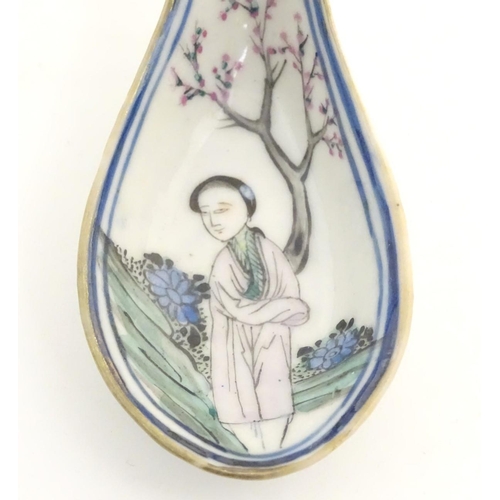 14 - A Chinese famille rose soup spoon decorated with a figure in a landscape with a cherry blossom tree.... 
