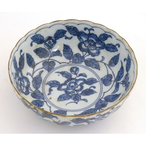 20 - A Chinese blue and white bowl with a lobed rim, decorated with flowers and foliage. Character marks ... 