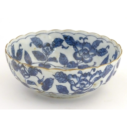 20 - A Chinese blue and white bowl with a lobed rim, decorated with flowers and foliage. Character marks ... 