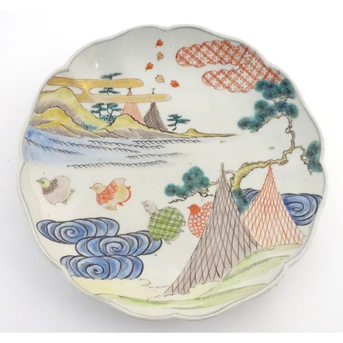 24 - A Chinese plate with a lobed rim, decorated with a landscape with stylised quail birds. Scrolling fo... 
