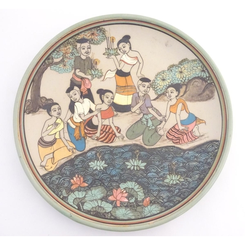 29 - An Oriental plate, the unglazed centre decorated with a group of people in a landscape relaxing near... 