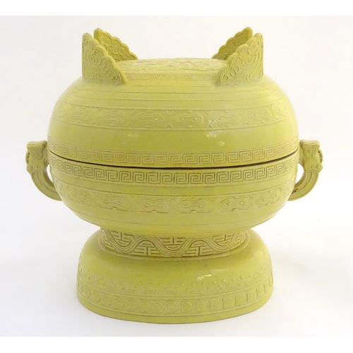 3 - A Chinese yellow ground lidded pot raised on a foot, with twin handles formed as stylised elephant h... 