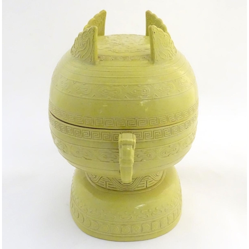 3 - A Chinese yellow ground lidded pot raised on a foot, with twin handles formed as stylised elephant h... 