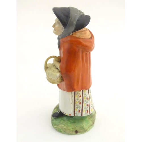 37A - An 18th / 19thC Staffordshire figure modelled as an old lady in a bonnet carrying basket. Approx. 7