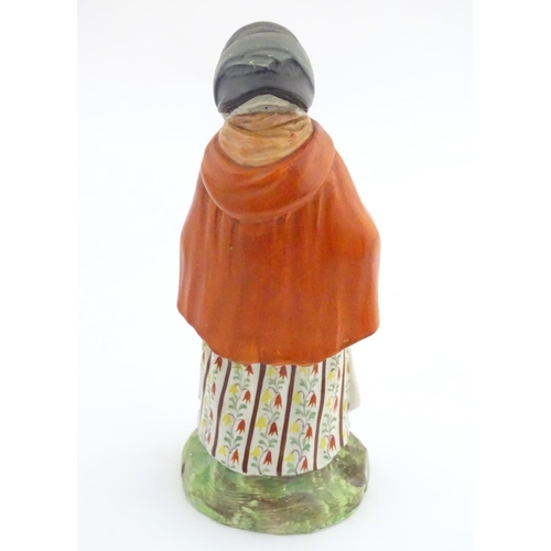 37A - An 18th / 19thC Staffordshire figure modelled as an old lady in a bonnet carrying basket. Approx. 7