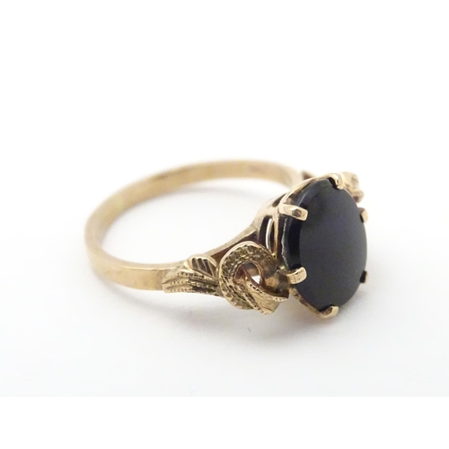411 - A 9ct gold ring set with black onyx cabochon. Ring size approx H.