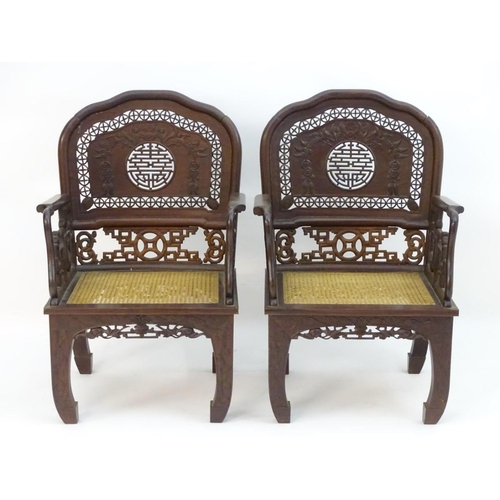 1174 - A pair of Chinese hardwood armchairs with pierced and carved backrests, fretwork supports and caned ... 