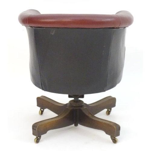 1175 - An early 20thC leather swivel armchair with an adjustable backrest and having four mahogany spokes a... 