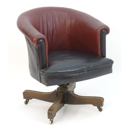 1175 - An early 20thC leather swivel armchair with an adjustable backrest and having four mahogany spokes a... 