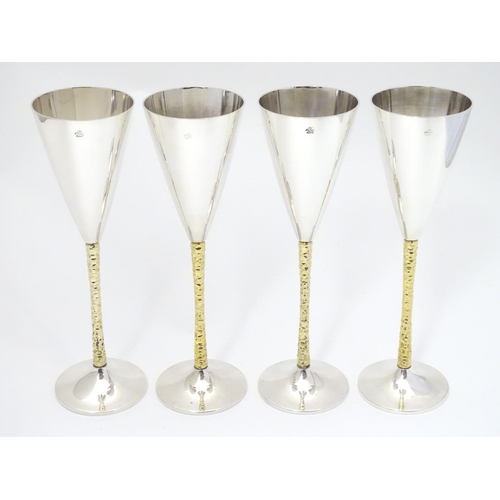 226 - A set of four Elizabeth II silver gilt Stuart Devlin champagne flutes, having flaring conical body w... 
