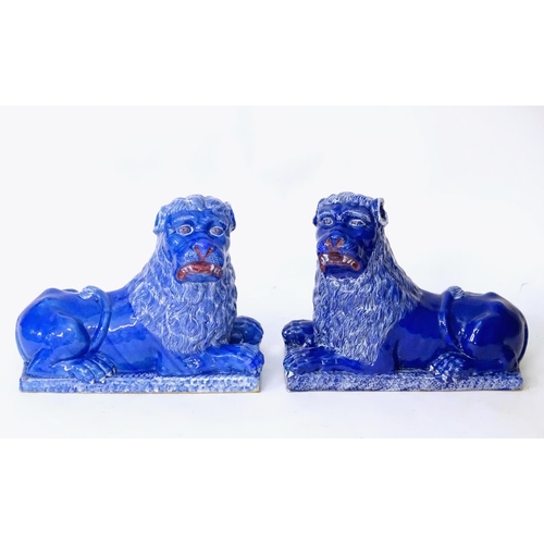 37 - A pair of 19thC faience Luneville lions with a cobalt blue glaze. Depicting recumbent lions on recta... 