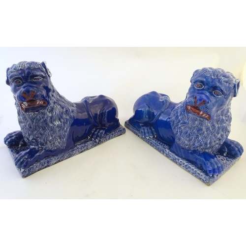 37 - A pair of 19thC faience Luneville lions with a cobalt blue glaze. Depicting recumbent lions on recta... 