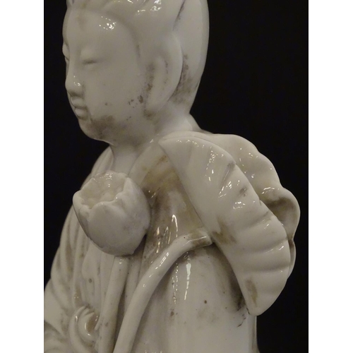 8 - A Chinese blanc de chine figure of Guanyin holding flowers, raised on a base of lotus flowers and li... 