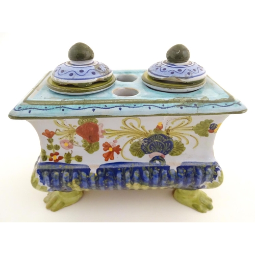 72 - A Continental faience inkwell of sarcophagus form  on four paw feet with hand painted floral decorat... 