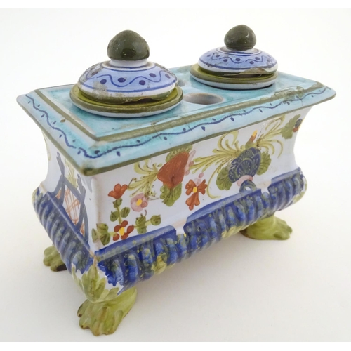 72 - A Continental faience inkwell of sarcophagus form  on four paw feet with hand painted floral decorat... 