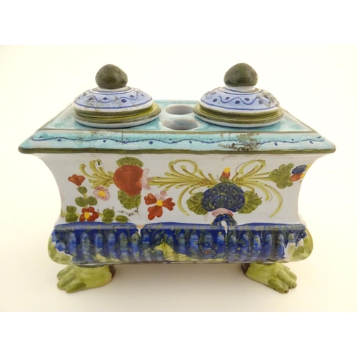 72 - A Continental faience inkwell of sarcophagus form  on four paw feet with hand painted floral decorat... 