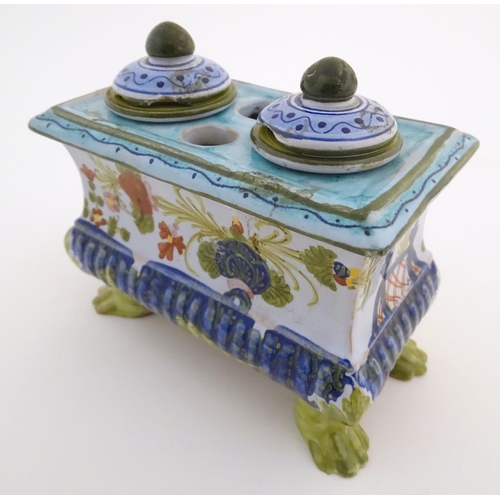 72 - A Continental faience inkwell of sarcophagus form  on four paw feet with hand painted floral decorat... 