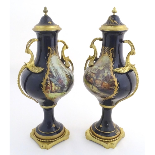 131 - A matched pair of Sevres style lidded urn garnitures on mounted bases, with cobalt blue bodies with ... 