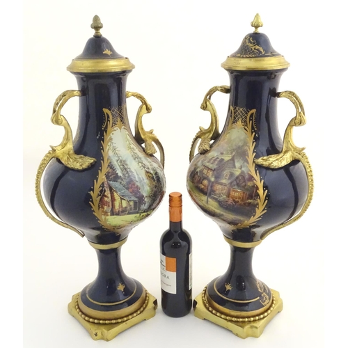 131 - A matched pair of Sevres style lidded urn garnitures on mounted bases, with cobalt blue bodies with ... 