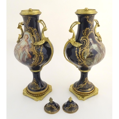 131 - A matched pair of Sevres style lidded urn garnitures on mounted bases, with cobalt blue bodies with ... 