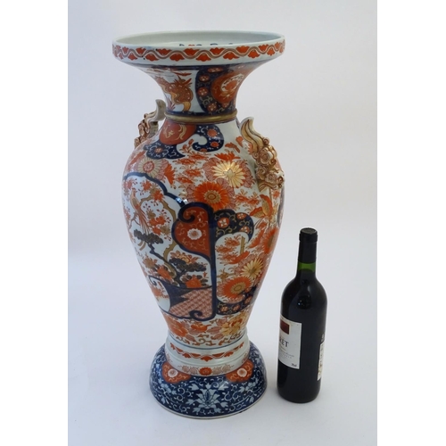 115 - A large Oriental baluster vase with a flared rim and twin handles formed as stylised clouds. Decorat... 