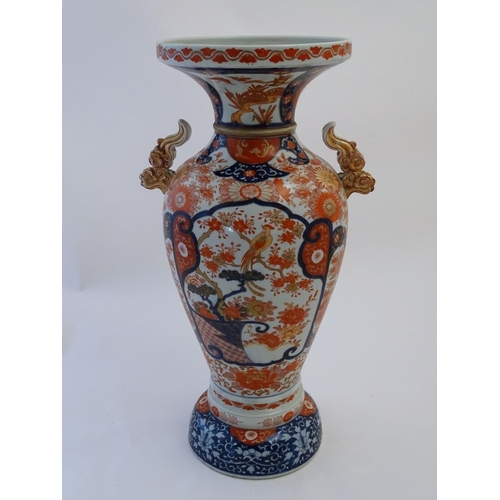 115 - A large Oriental baluster vase with a flared rim and twin handles formed as stylised clouds. Decorat... 