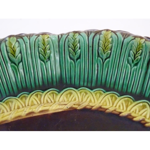 117 - A pair of Victorian majolica bread plates, the inner rim decorated with wheat sheaves, the outer edg... 