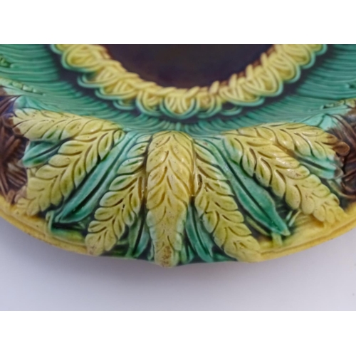 117 - A pair of Victorian majolica bread plates, the inner rim decorated with wheat sheaves, the outer edg... 