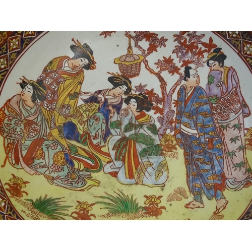 126 - A large Japanese bowl with hand painted decoration the central roundel depicting figures / geisha gi... 