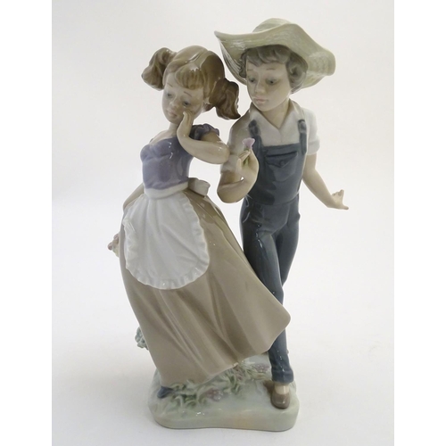 79 - A Lladro figural group depicting a girl and boy with flowers, Love in Bloom, model no. 5292. Approx.... 