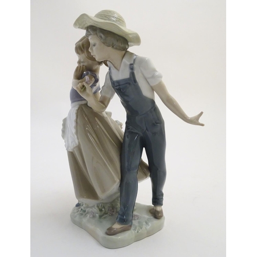 79 - A Lladro figural group depicting a girl and boy with flowers, Love in Bloom, model no. 5292. Approx.... 