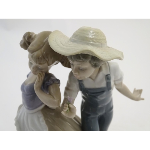 79 - A Lladro figural group depicting a girl and boy with flowers, Love in Bloom, model no. 5292. Approx.... 