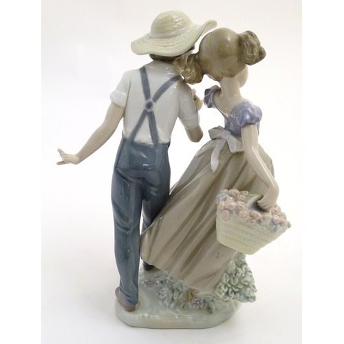 79 - A Lladro figural group depicting a girl and boy with flowers, Love in Bloom, model no. 5292. Approx.... 